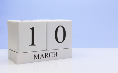 March 10st. Day 10 of month, daily calendar on white table with reflection, with light blue background. Spring time, empty space for text