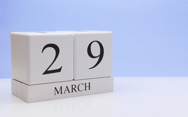 March 29st. Day 29 of month, daily calendar on white table with reflection, with light blue background. Spring time, empty space for text