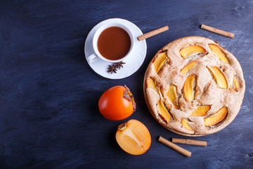 Sweet persimmon pie on black wooden background.