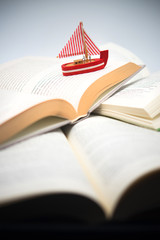 boat navigating between books, traveling, reading, adventures in books