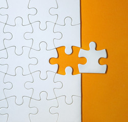 Obraz premium Unfinished white puzzle pieces on orange background