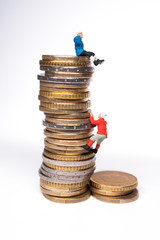 Miniature climbers climbing on the stack of coins