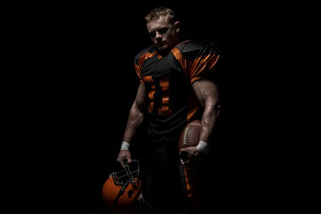 American football player on a dark background in black and orange equipment.