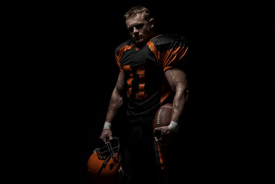 American football player on a dark background in black and orange equipment.