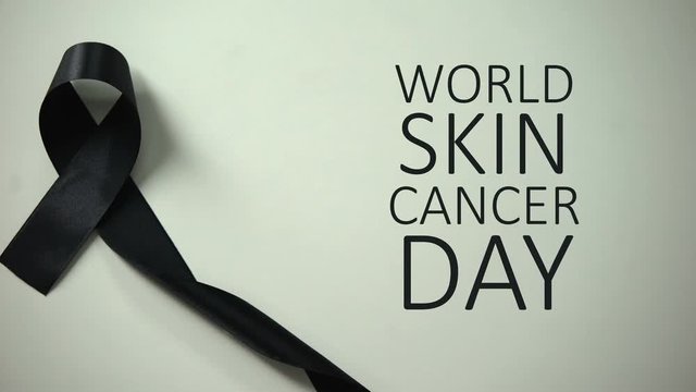 World skin cancer day inscription, black ribbon on table, melanoma awareness