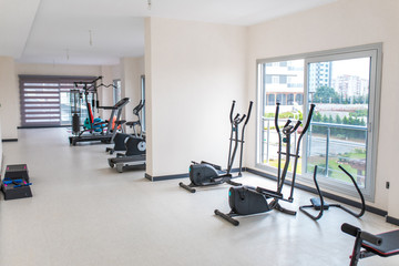 Fototapeta na wymiar Gym interior and exercise equipments. Apartment gym studio saloon interior
