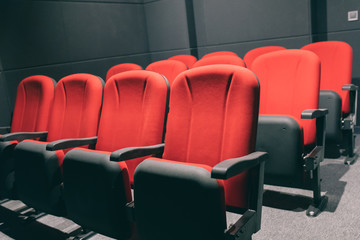 Obraz premium Cinema or movie auditorium with empty red seats or chairs
