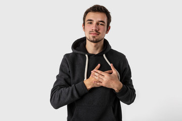 Thankful caucasian young man looking into the camera with hands on his heart. Isolated on white background.Gratitude concept.