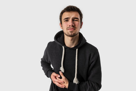 Young caucasian man having stomach aches looking into the camera. Isolated on white background. Stomachache concept.