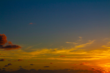sunset on the beach. The sun dyes the clouds in golden colors.