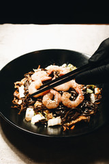 Delicious meal with shrimps in black plate, traditional asian  food 