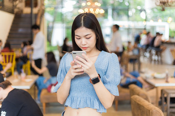 Young beautiful smart woman using cellphone in coffee shop for business, online shopping, financial, internet banking.