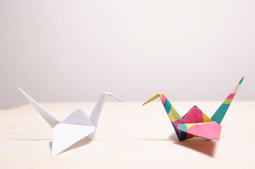 Creative concept, white origami opposite to colorful crane bird 