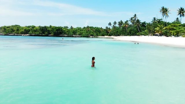 Aerial: Beautiful Young Woman in Bikini Walking in the Ocean by Stunning Beach