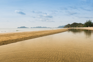 The sea is separated by sand dunes and mountains in the beautiful sky.