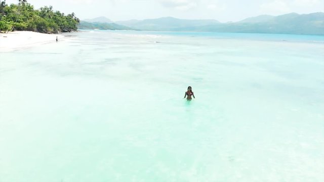 Aerial: Beautiful Woman in Crystal Clear Water with Mountains in the Distance