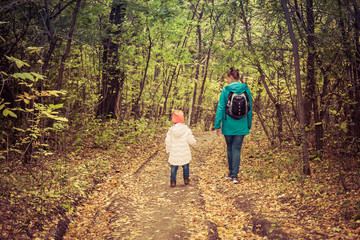 Obraz premium Mother and daughter are walking in the autumn forest