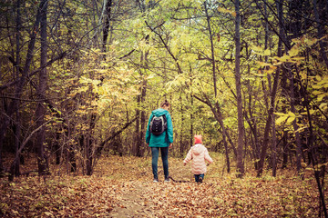 Fototapeta premium Mother and daughter are walking in the autumn forest