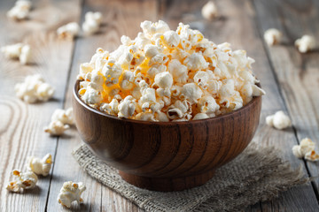 A wooden bowl of salted popcorn on rustic table.