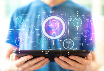 Question marks with young man using a tablet computer