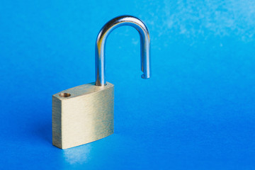 Close - up of padlock, in open position on blue background. Selective focus.