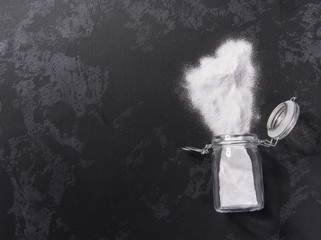 Jar of baking soda on a black background.Flat lay