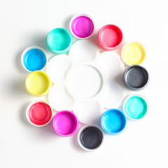 Composition from cans of acrylic paints and a palette. white background, view from the top, close-up