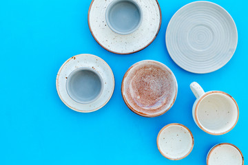 Kitchen concept. Crockery kit. Empty ceramic plates and mugs on blue background top view copy space
