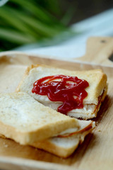 Ham cheese sandwich and tomato ketchup on wood tray and space for write wording, easy delicious food served with coffee or tea in coffee shop or office, popular food for office worker, time saving
