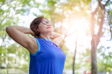 Senior asian woman relaxed listening to music in the park, Exercise sport activity concept