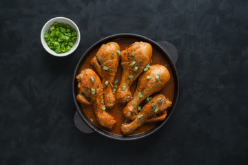 Legs of the chicken in the sauce in the pan.