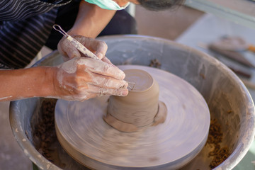 Close-up detail view at an artist makes clay pottery on a spin wheel.