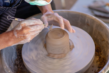 Close-up detail view at an artist makes clay pottery on a spin wheel.