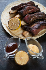 Barbecued beef ribs served with dipping sauces and tortilla flatbread, selective focus, vertical shot