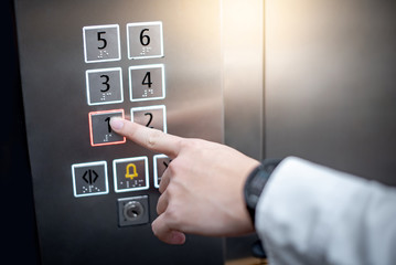 Male forefinger (index finger) pressing on the first floor button or floor number one in elevator (lift). Mechanical engineering concept © zephyr_p