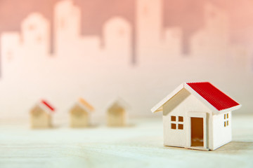 Real estate or property investment. Home design concept. Wooden house models on the table with city skyline background. Residential building development
