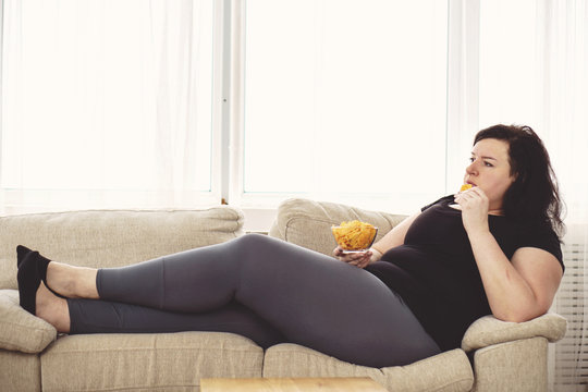 lack of physical activity,sedentariness, imbalanced nutrition, laziness, homebody. fat woman overeating junk food