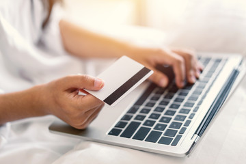 Young woman working on a laptop and uses credit card, bussiness and shopping concept