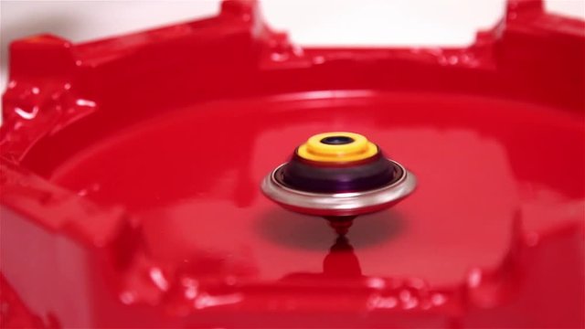Popular Modern Children Game Beyblade Burst Fast spinning on red arena. Gyroscope, spinner Japanese toy