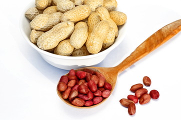 Peanuts in bowl and in wooden spoon on white background