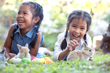 Happy asian child girls playing with little bunny rabbit with love and tenderness in the garden at...