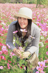 Portrait of smiling asian female smelling blooming flowers