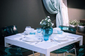 home interior of the served table. in the center of the table is a vase with white roses. in the background hang curtains