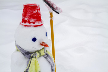 Snowman in red hat and scarf made by children. Closeup, selective focus