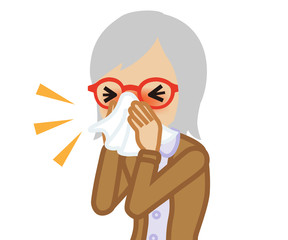 Senior woman blowing nose with a tissue