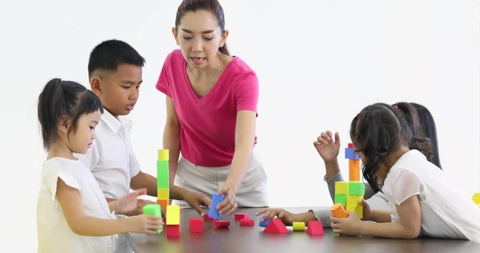 Close up scene video of Asian teacher lets Asian students playing colorful wooden blocks toy together, concept for classroom.