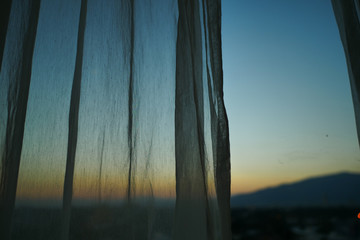 sunlight through white curtain with sunset sky view outside the window