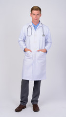 Full body shot of young handsome man doctor with blond hair