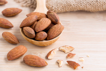 Almonds nut peeled on the wooden spoon with sackcloth on wood table background.
