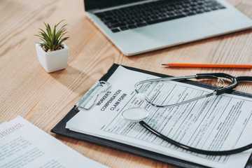 clipboard with compensation claim form and stethoscope on office desk